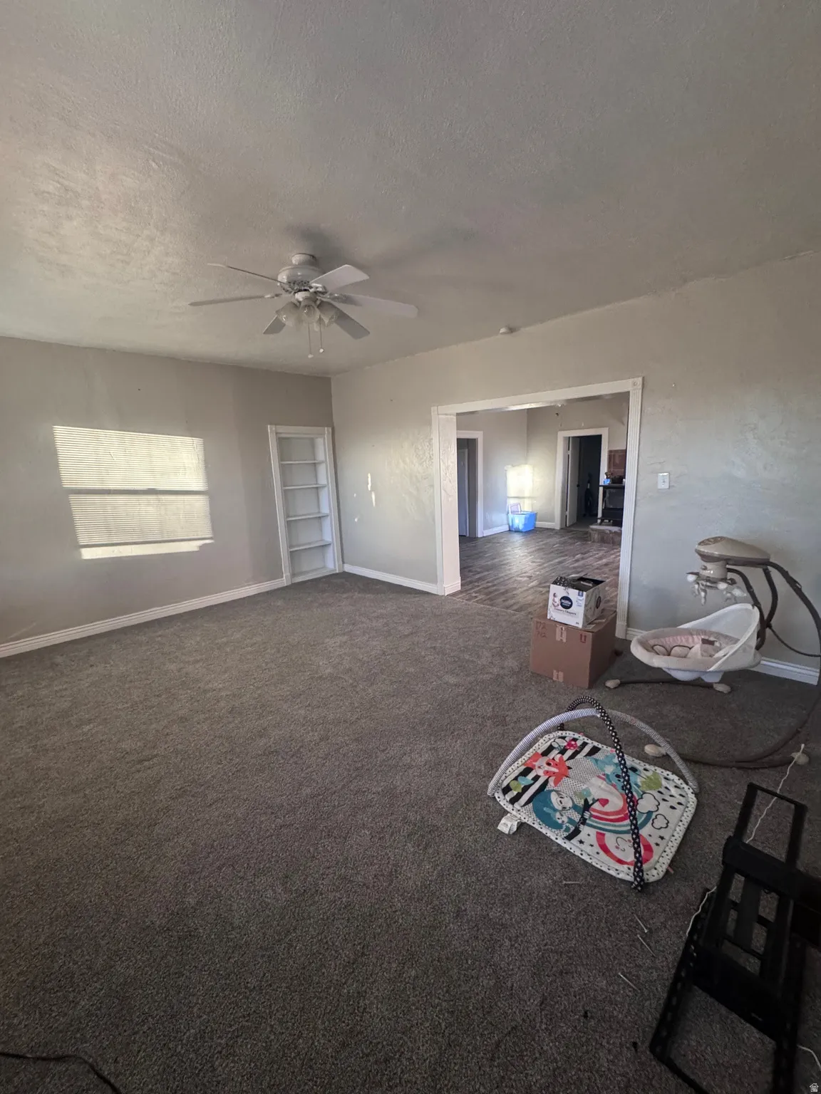 Living room featuring dark carpet, a textured ceiling, and ceiling fan