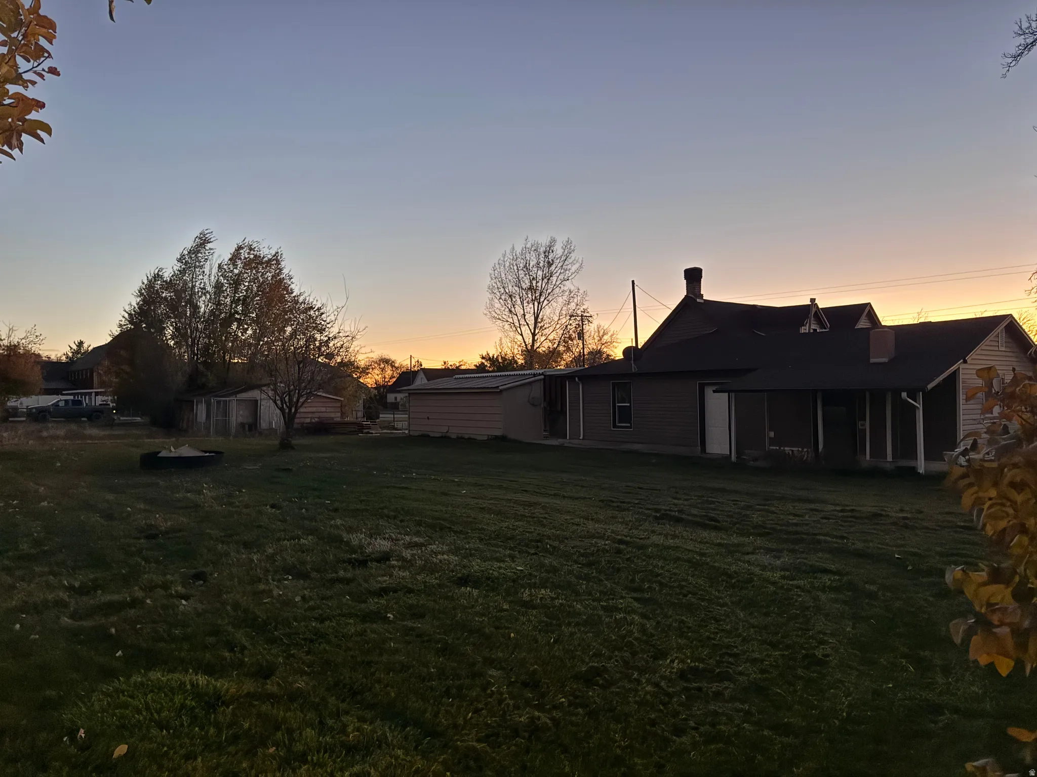 Back of property at dusk with a lawn