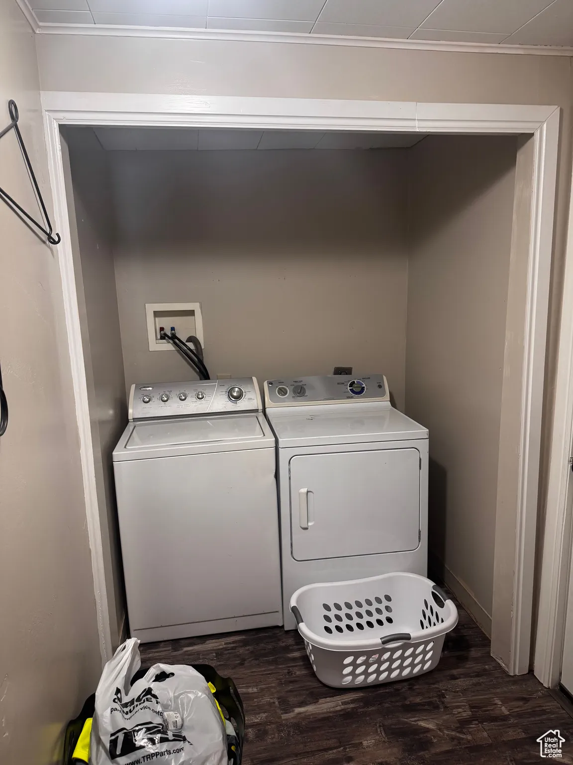 Laundry room with dark wood finished floors, separate washer and dryer, and crown molding