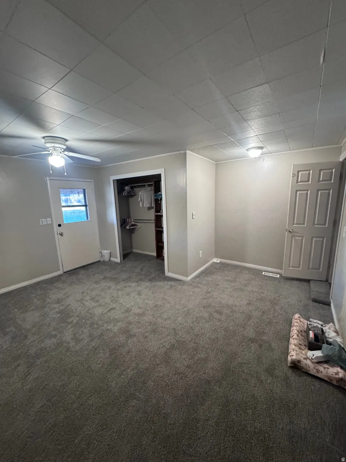 Basement with carpet floors, a ceiling fan, and a paneled ceiling