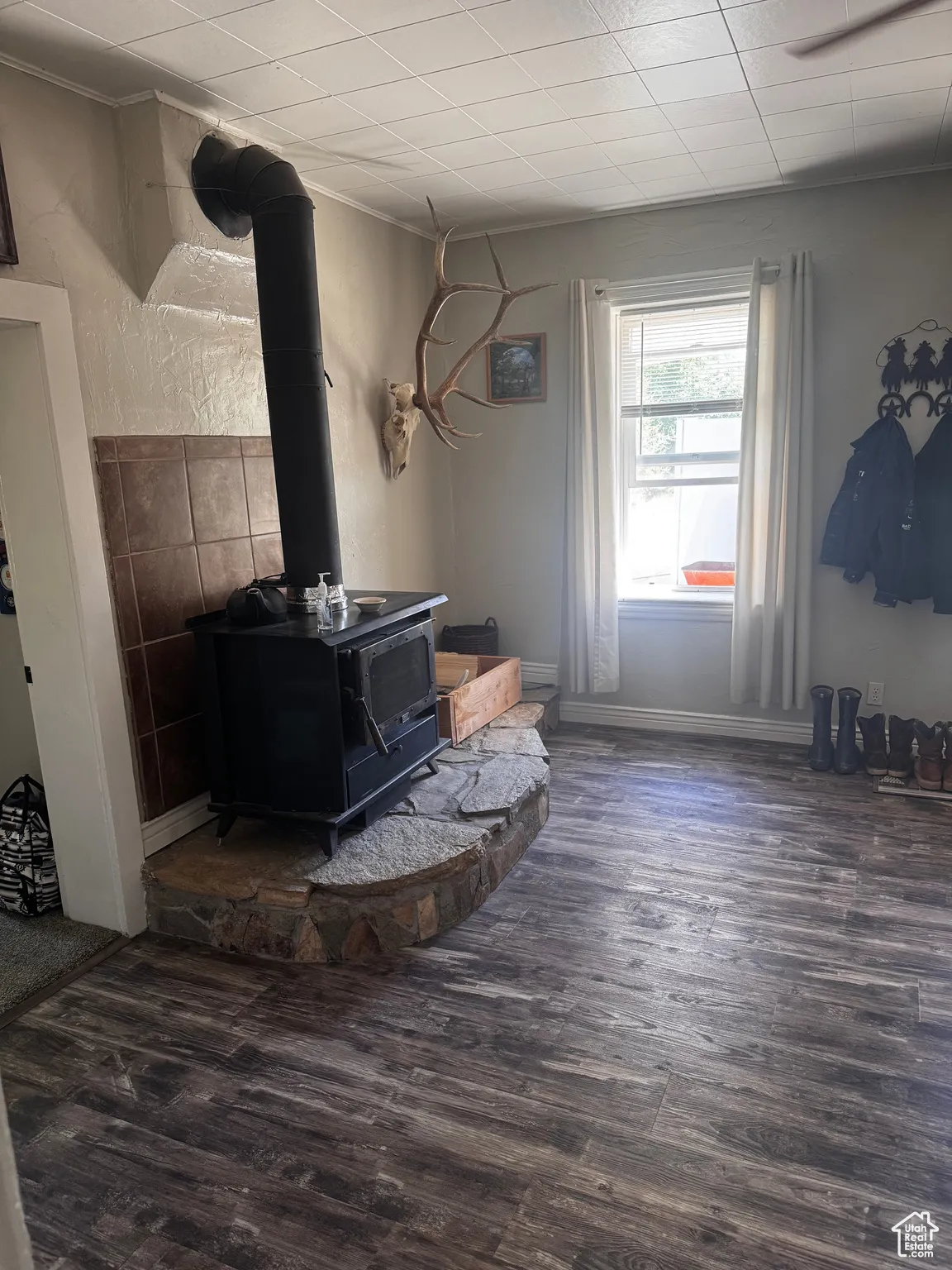Living room with a wood stove, wood finished floors, and crown molding