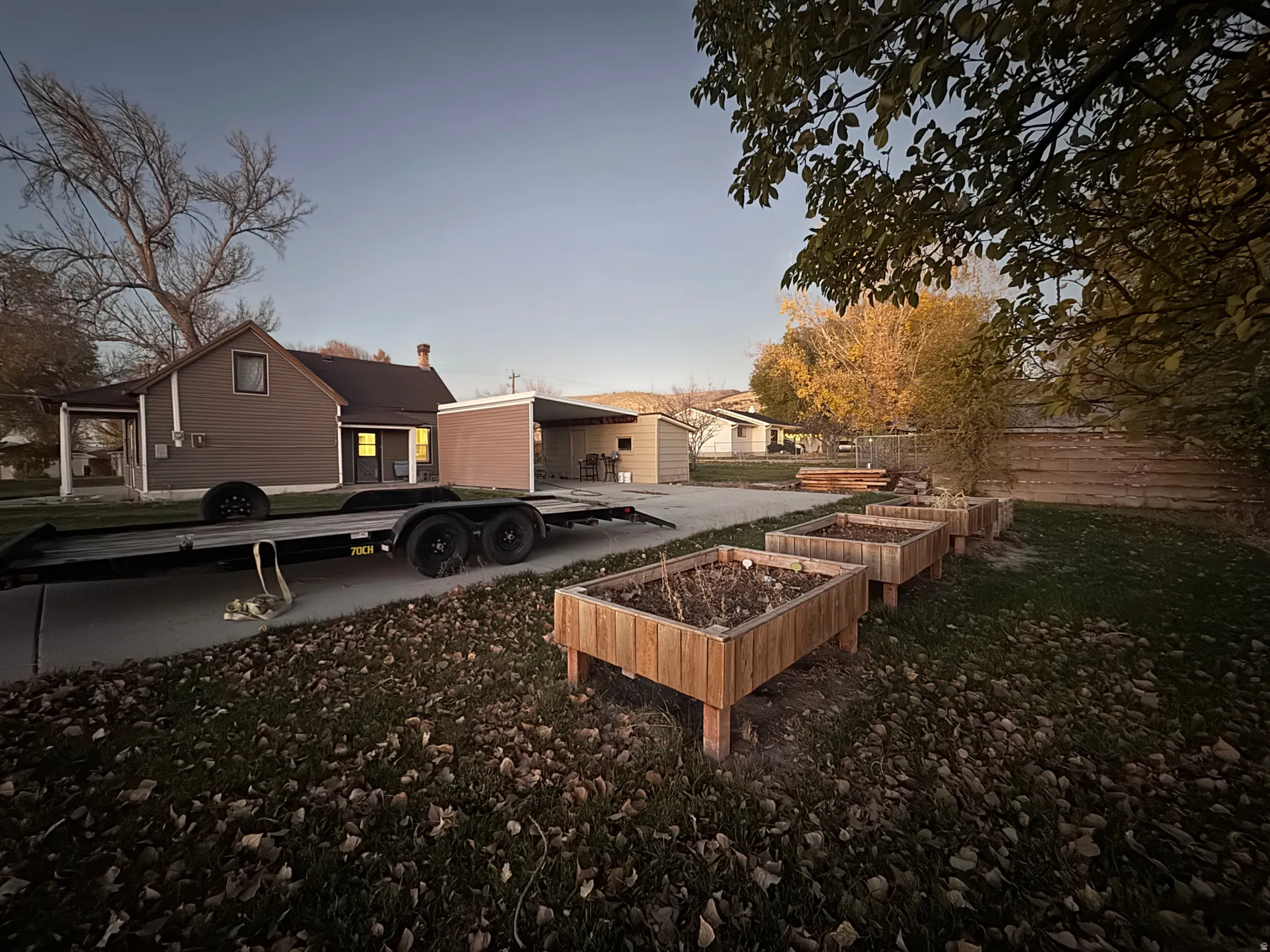 Back of house at dusk featuring a vegetable garden, a chimney, and a residential view