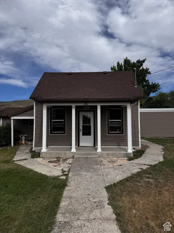 Bungalow featuring covered porch, a front yard, and a shingled roof