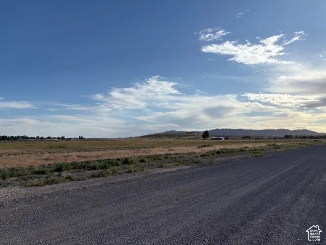 View of asphalt road with a view of rural / pastoral area and a mountain view