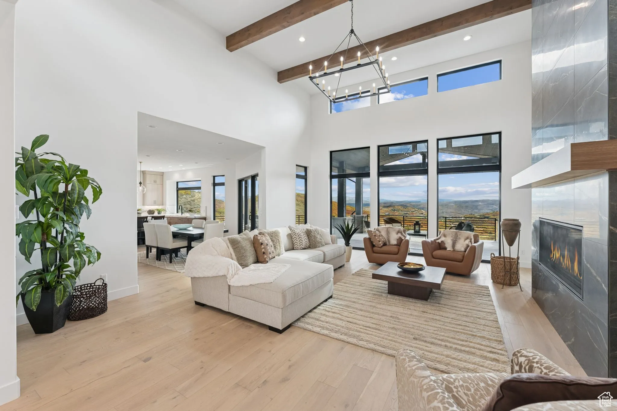 Living room with light wood-type flooring, a premium fireplace, beam ceiling, a high ceiling, and recessed lighting