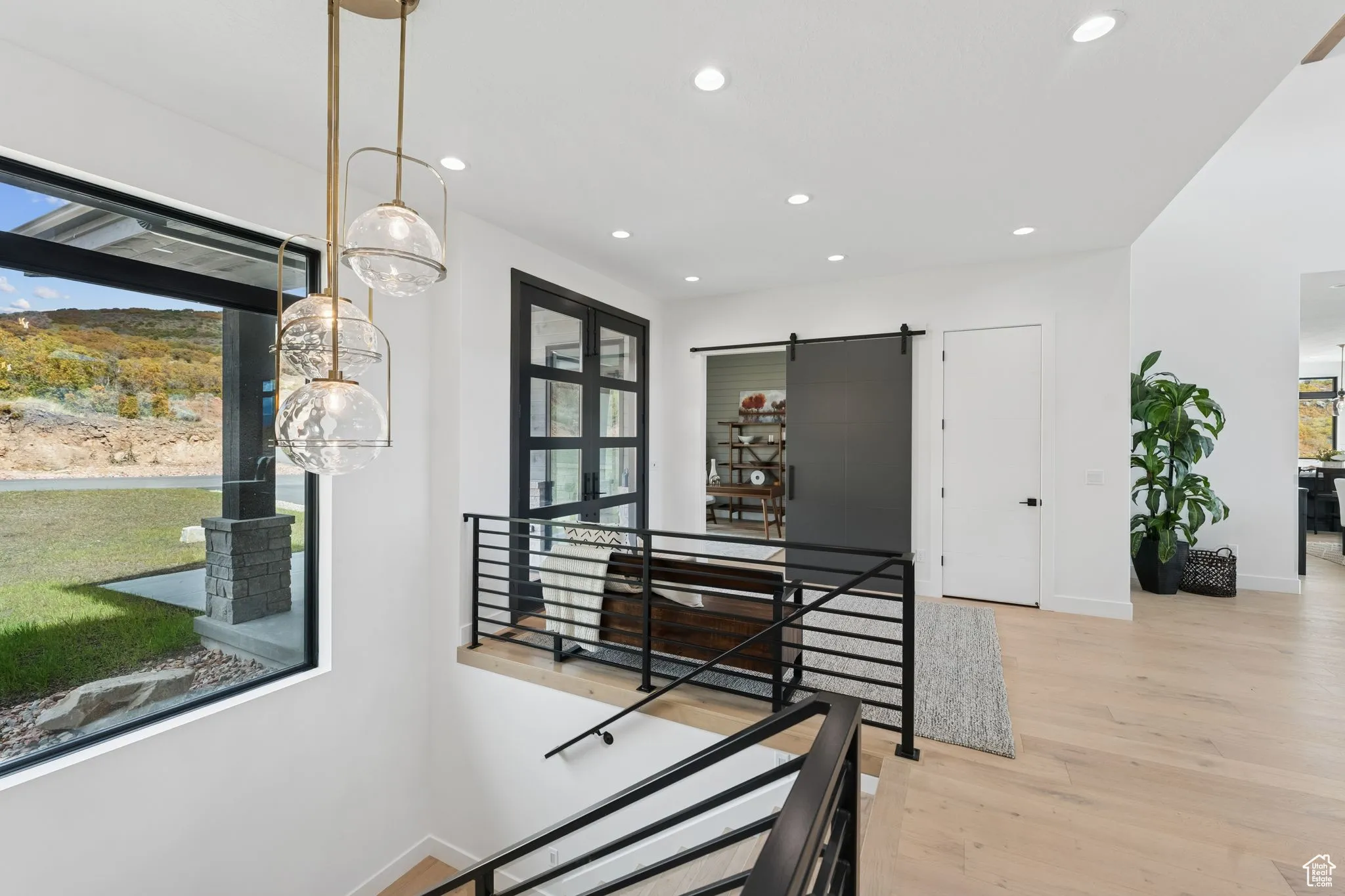 Dining area with a barn door, light wood finished floors, and recessed lighting