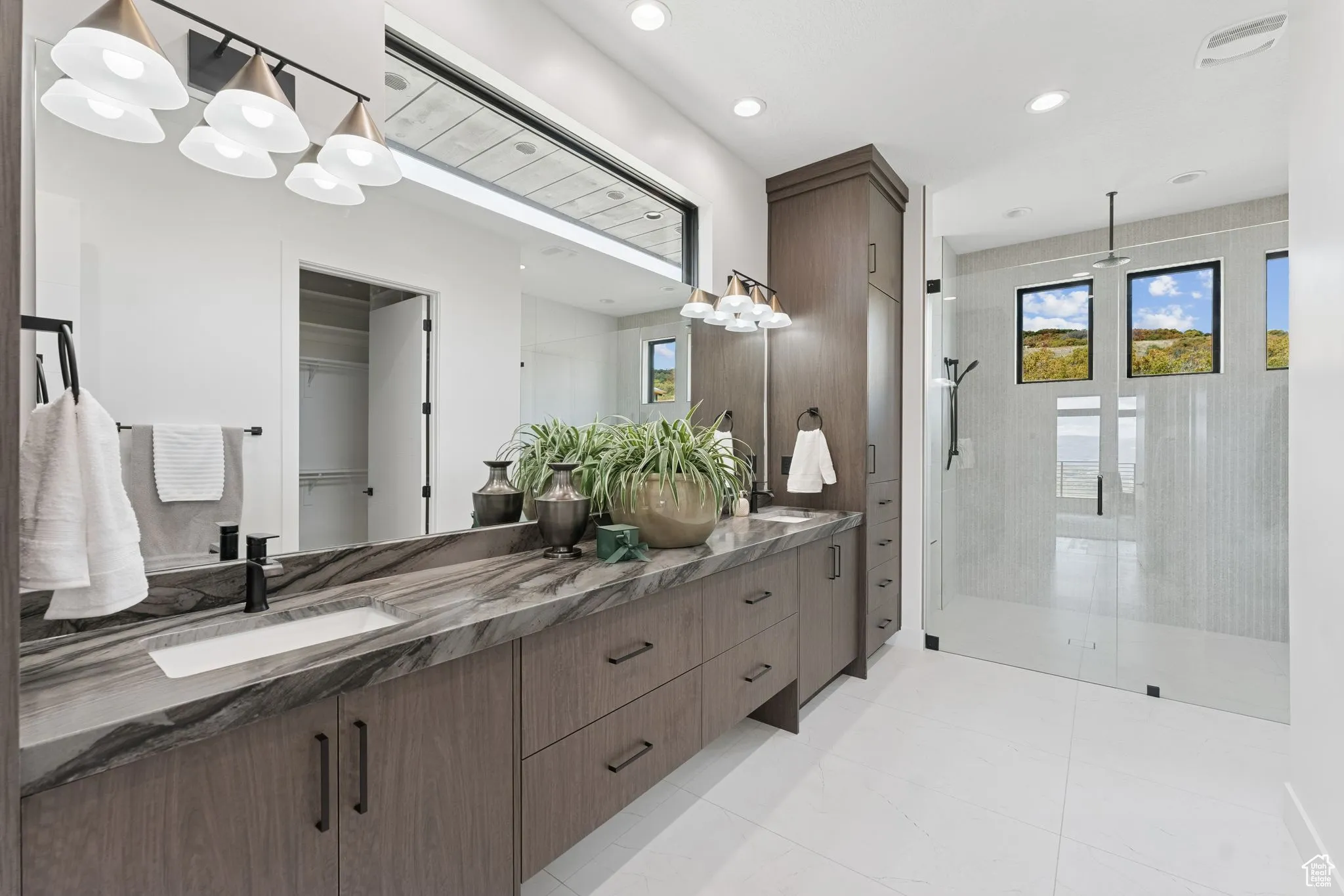 Bathroom featuring a shower stall, double vanity, recessed lighting, a spacious closet, and light tile patterned floors