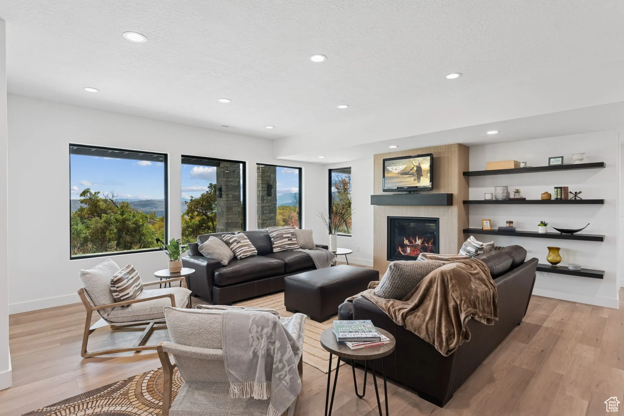 Living area with recessed lighting, a glass covered fireplace, light wood-style flooring, and a textured ceiling