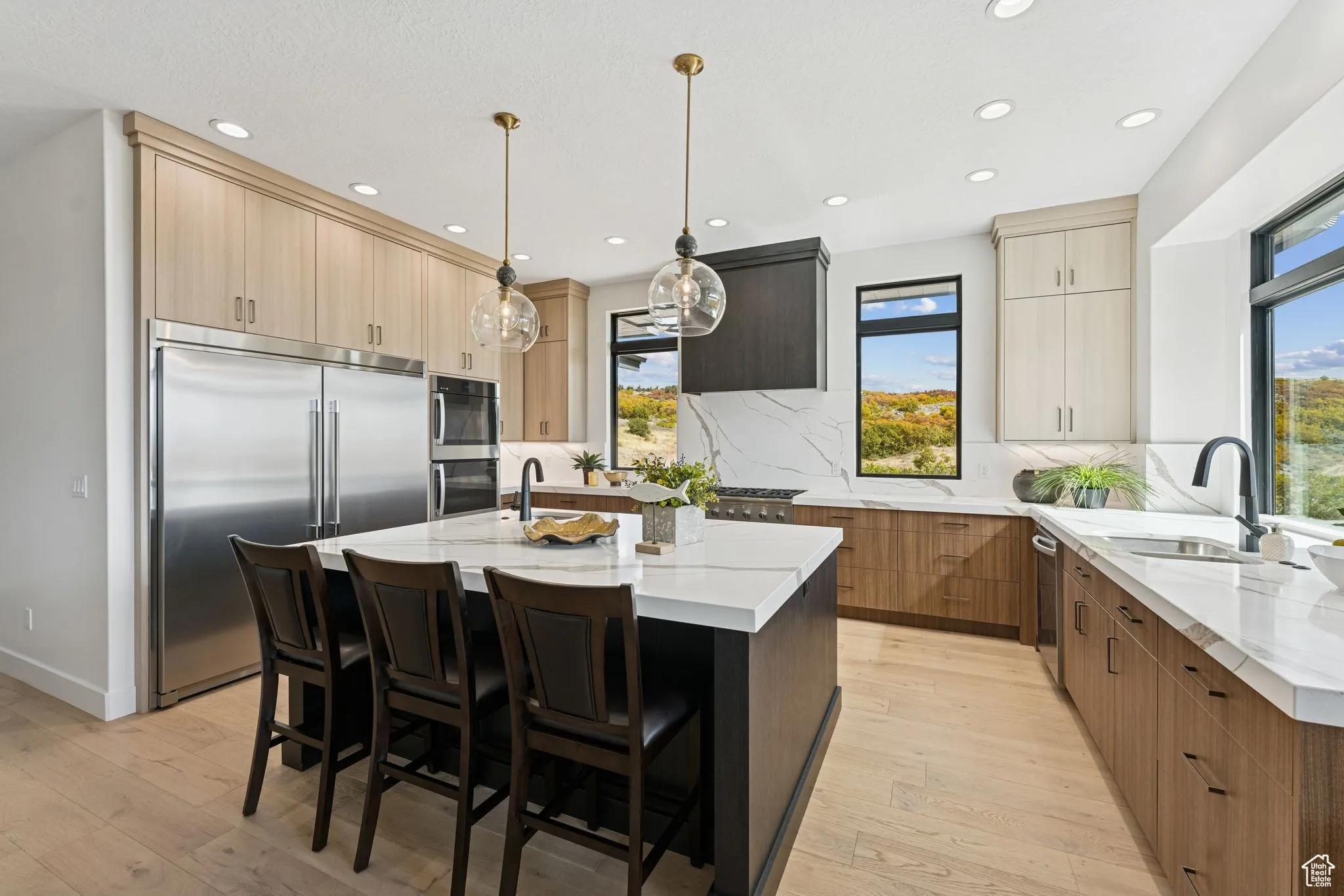 Kitchen with light stone counters, appliances with stainless steel finishes, a kitchen breakfast bar, a center island with sink, and recessed lighting