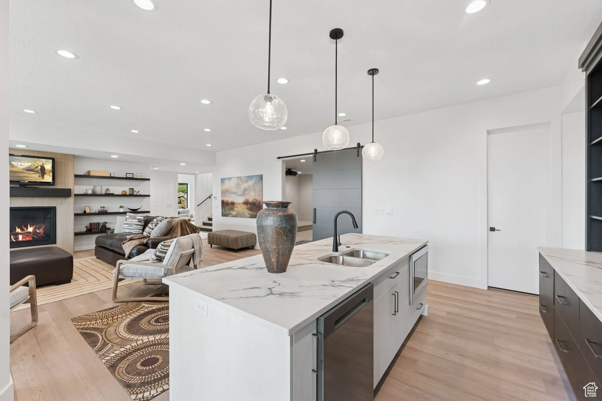 Kitchen with a barn door, decorative light fixtures, light stone countertops, light wood-style flooring, and recessed lighting