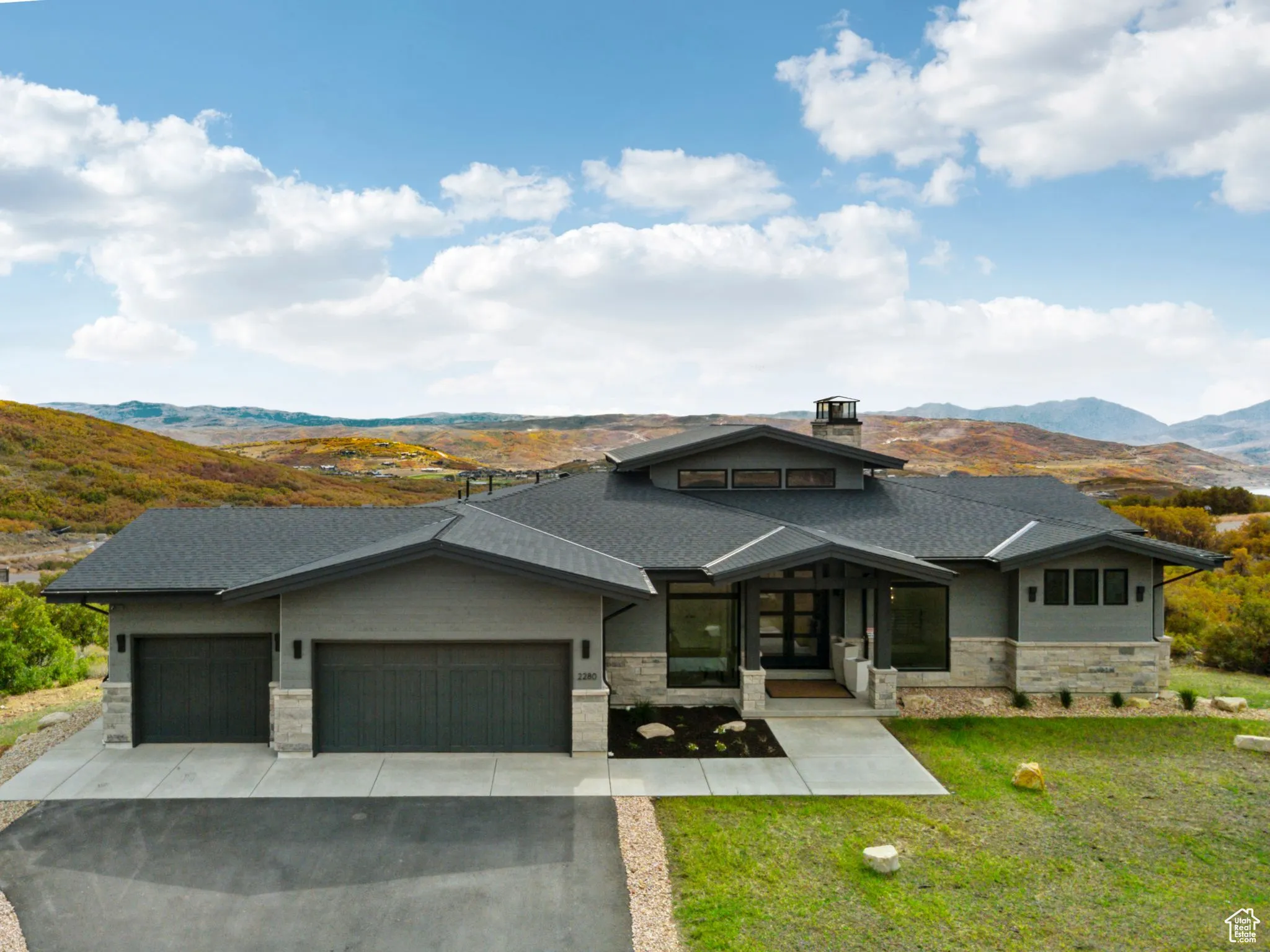 Prairie-style home with a mountain view, an attached garage, driveway, and a front lawn