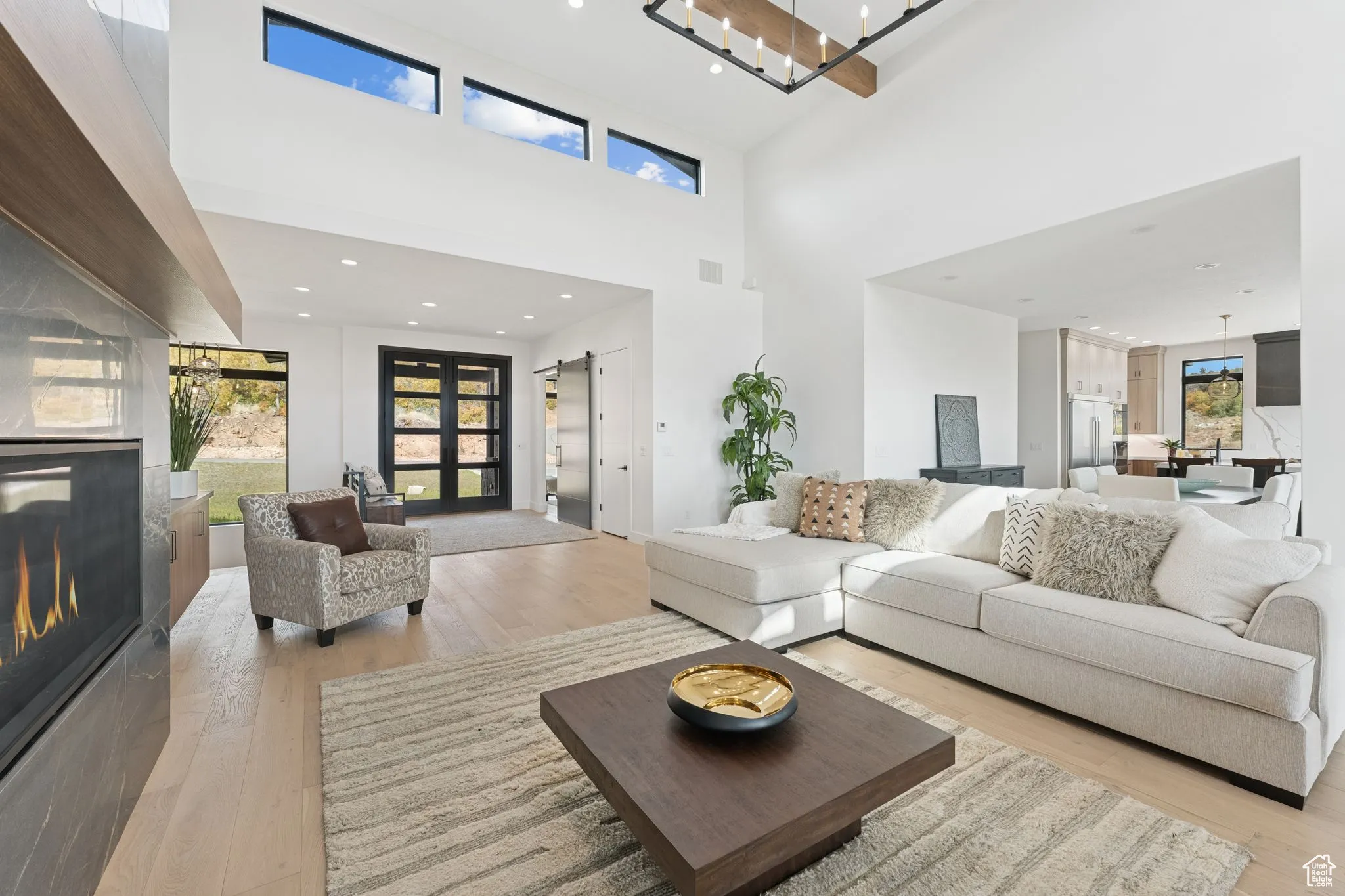 Living room with a glass covered fireplace, light wood-style flooring, a high ceiling, and recessed lighting