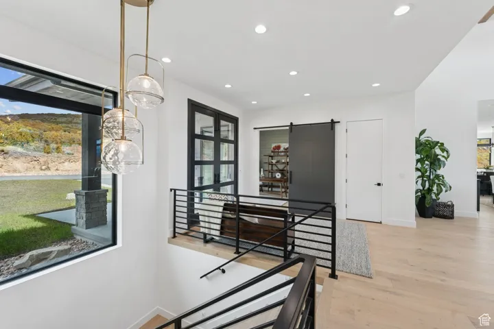 Dining area with a barn door, light wood finished floors, and recessed lighting