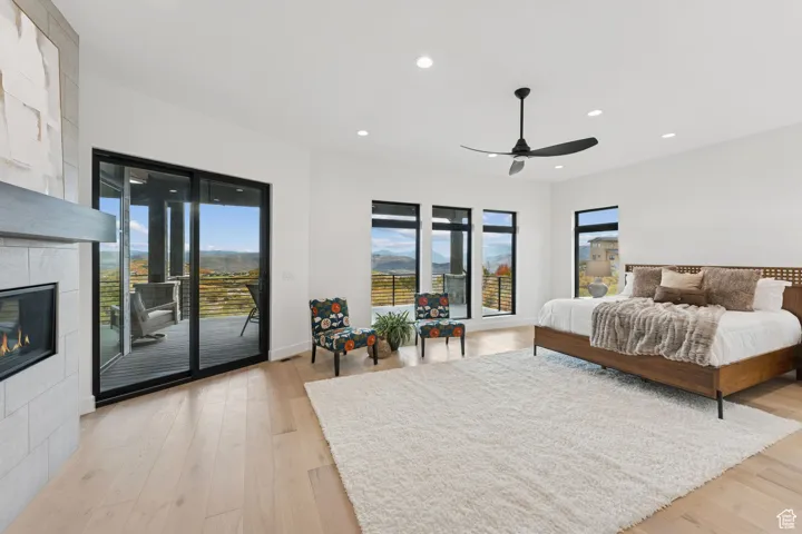 Bedroom featuring recessed lighting, light wood-style floors, access to outside, a fireplace, and ceiling fan