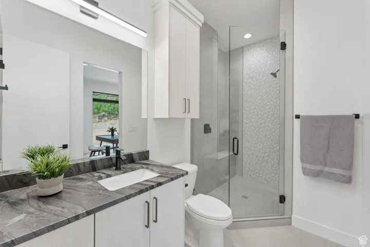 Bathroom featuring vanity, tile patterned flooring, a shower stall, and recessed lighting