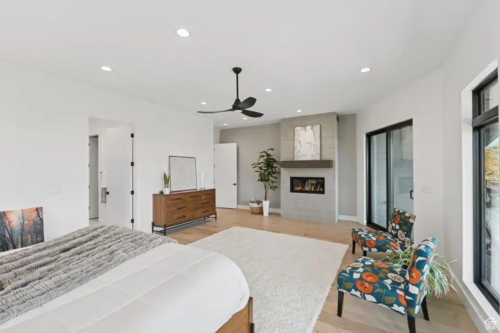 Bedroom featuring light wood-style flooring, recessed lighting, a tiled fireplace, and ceiling fan