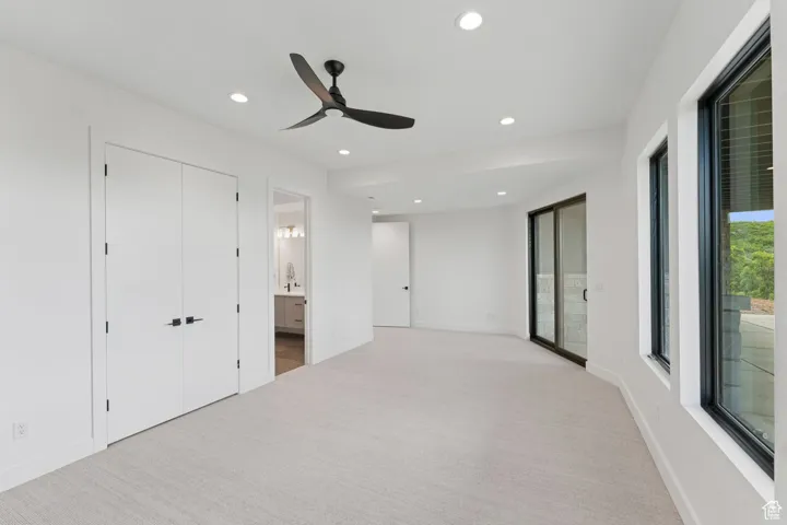 Unfurnished bedroom with light colored carpet, recessed lighting, connected bathroom, and ceiling fan