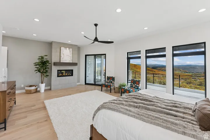 Bedroom with recessed lighting, light wood-style flooring, a fireplace, a mountain view, and access to exterior