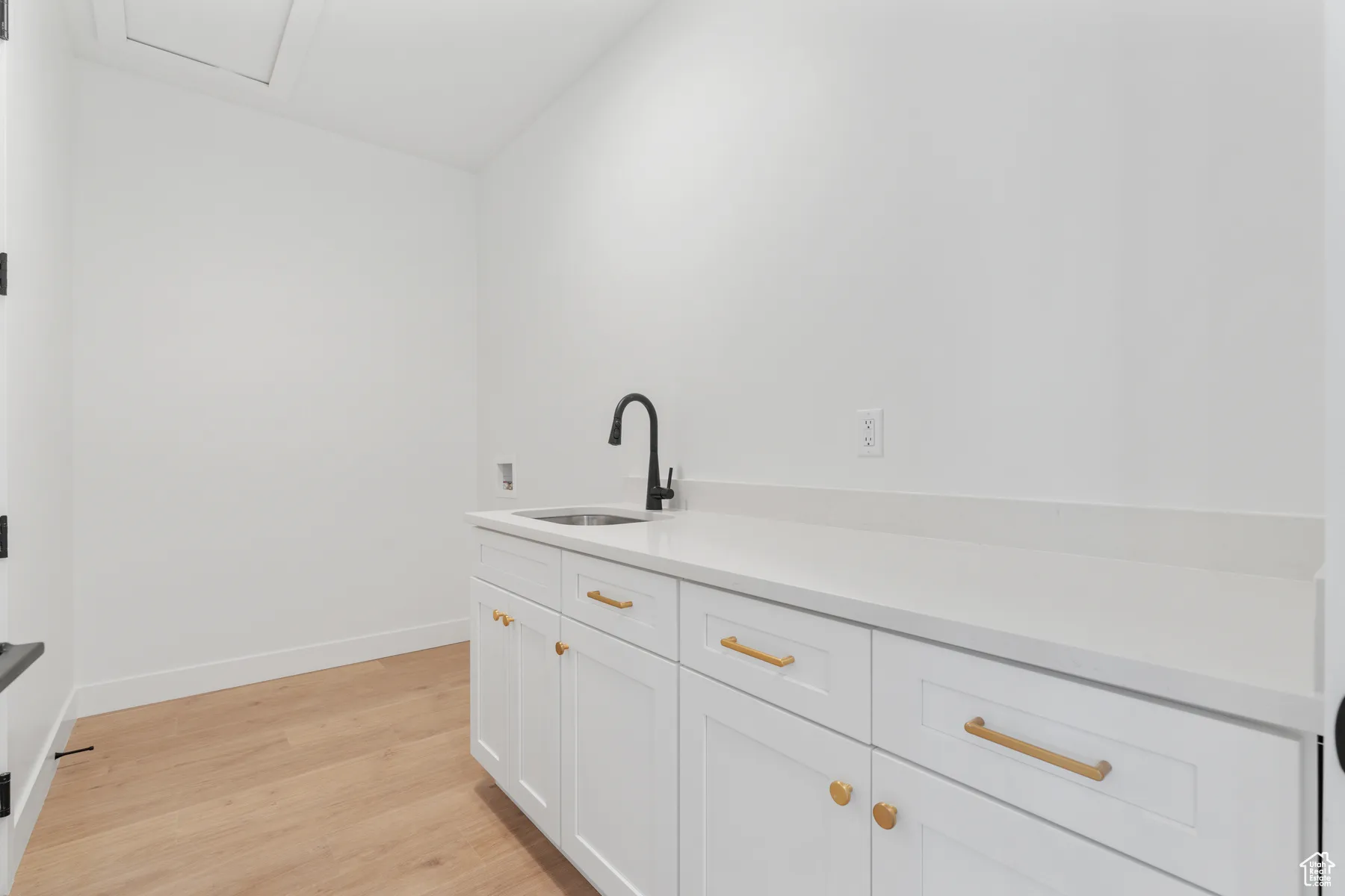 Bar area featuring a sink and light wood-style flooring