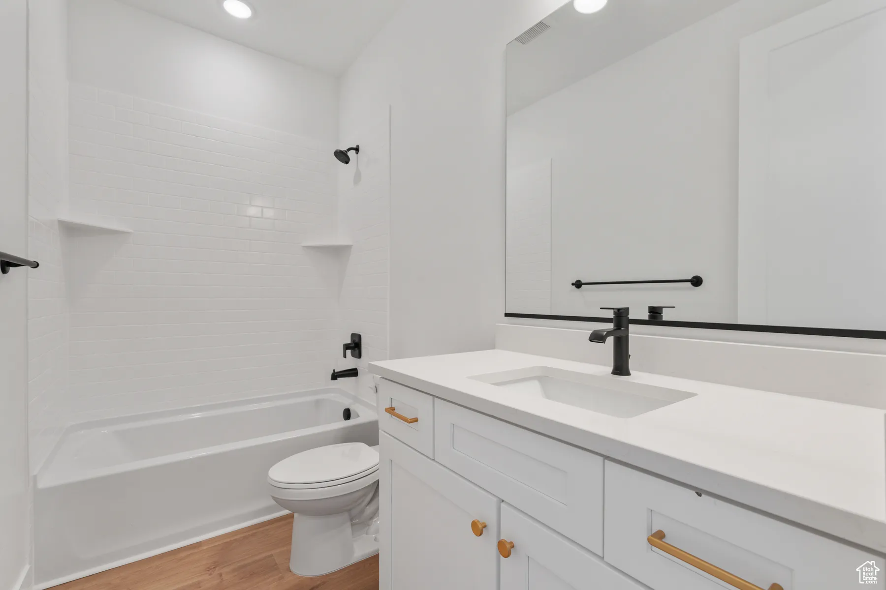 Bathroom with wood finished floors, vanity, shower / bath combination, and recessed lighting