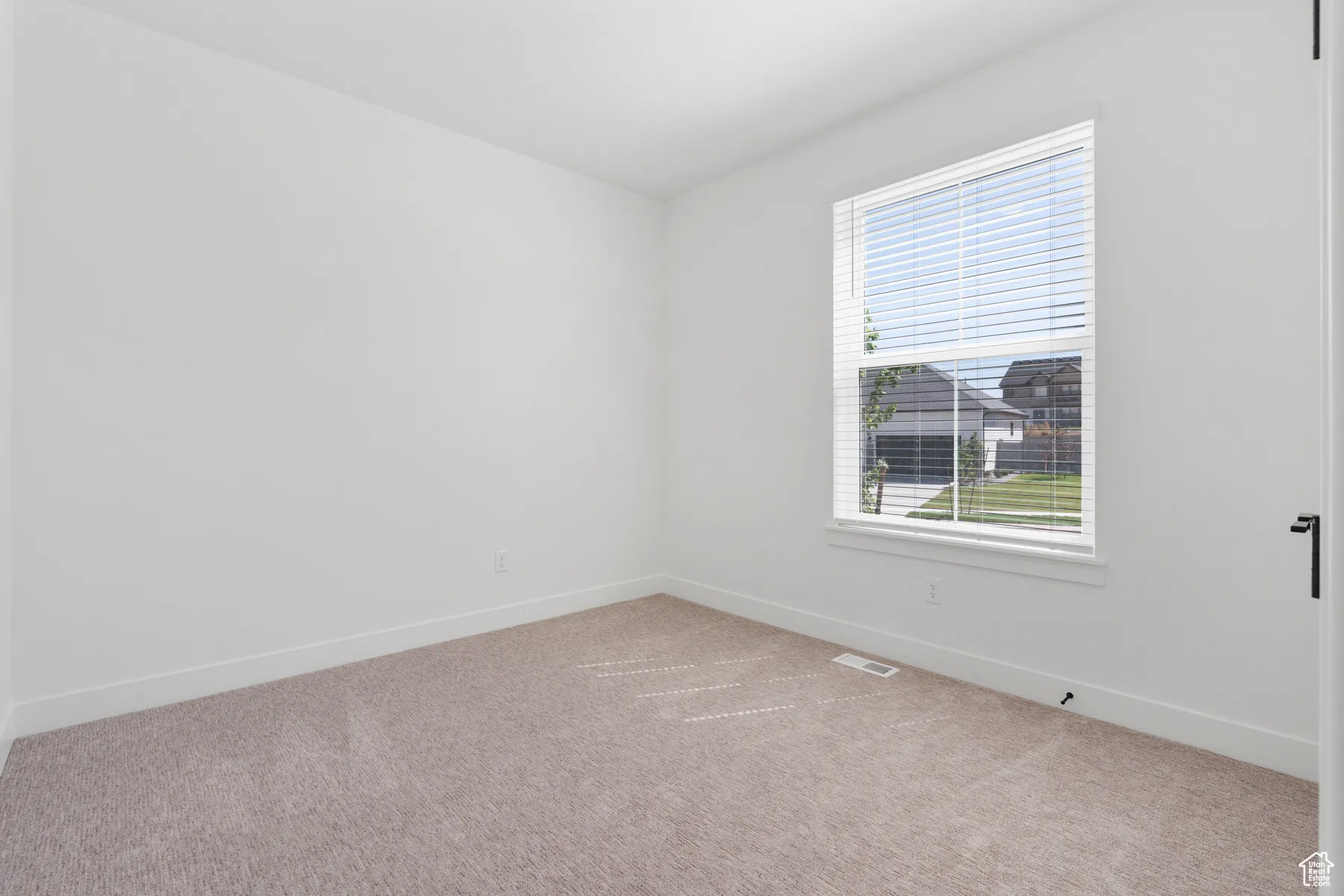 Empty room featuring light colored carpet and baseboards