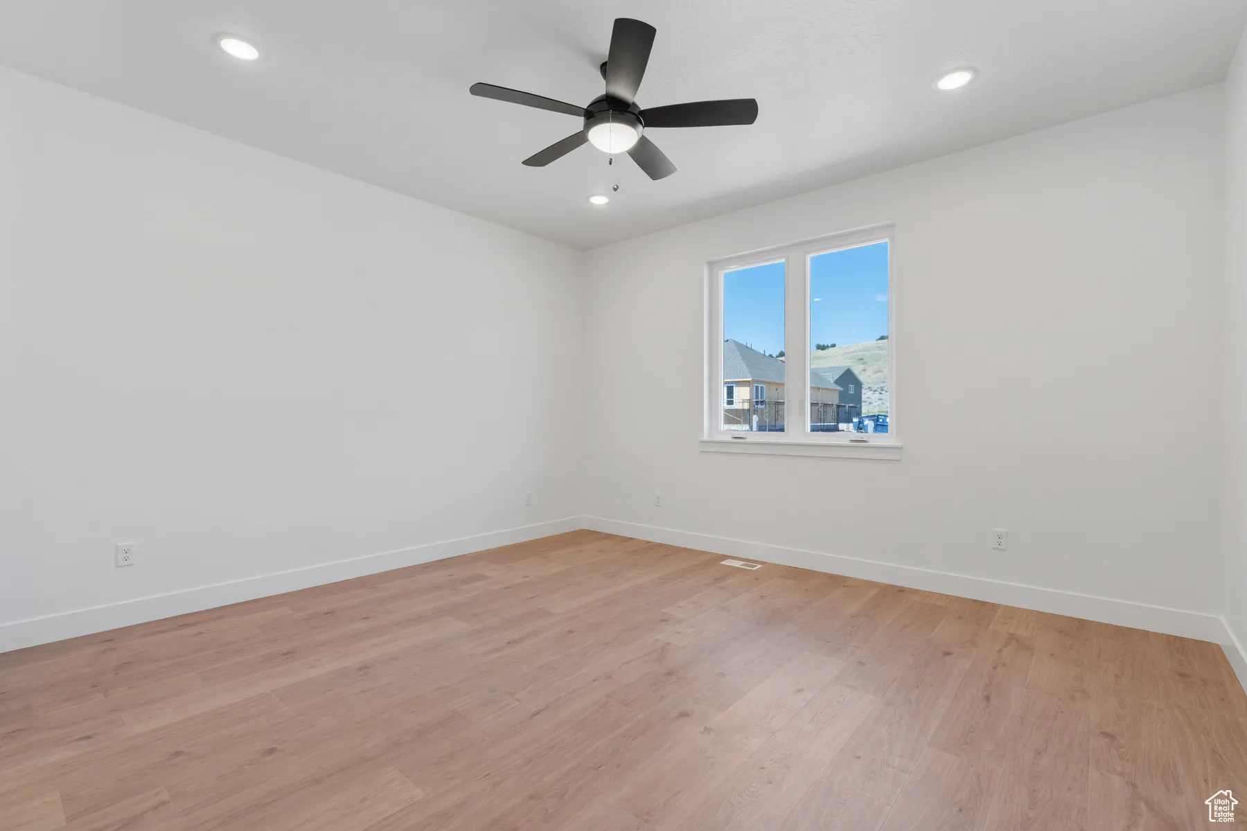 Spare room featuring light wood finished floors, ceiling fan, and recessed lighting