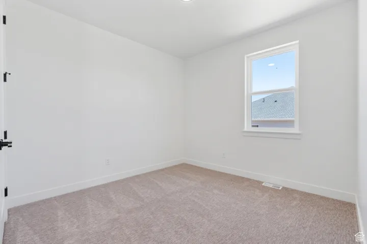 Spare room with light colored carpet and baseboards