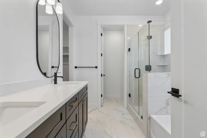 Bathroom with marble finish flooring, double vanity, a stall shower, recessed lighting, and a bath