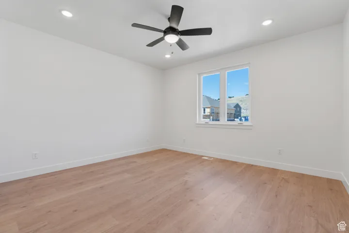 Spare room featuring light wood finished floors, ceiling fan, and recessed lighting