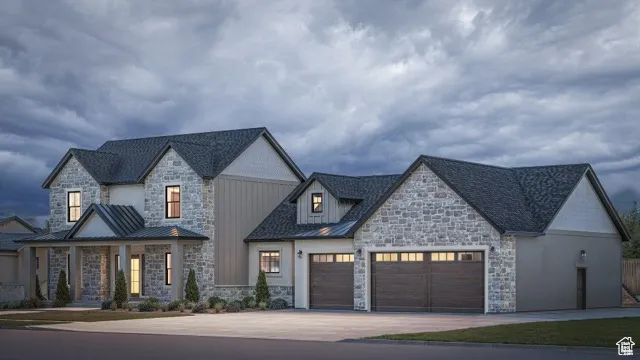 View of front facade with stone siding, a garage, driveway, and a standing seam roof