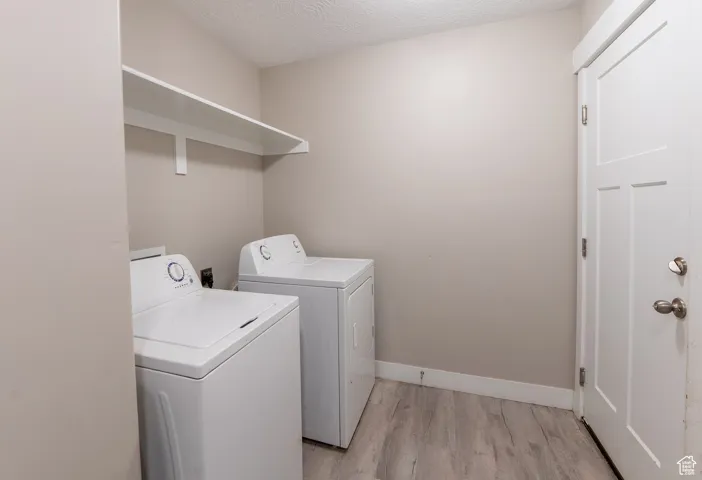 Washroom featuring washing machine and clothes dryer and light wood-style flooring