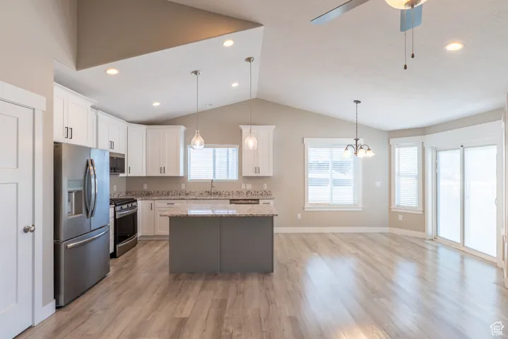 Kitchen with appliances with stainless steel finishes, a kitchen island, vaulted ceiling, white cabinetry, and a ceiling fan