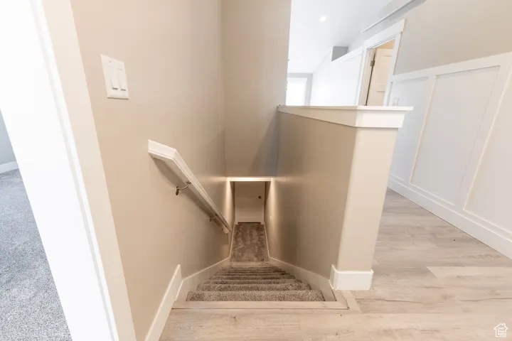 Stairway with wood finished floors and baseboards