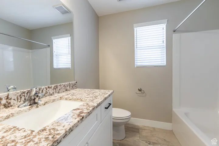 Bathroom with marble finish floors, vanity, and tub / shower combination