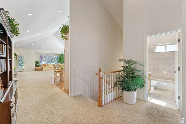 Hall with carpet, an upstairs landing, recessed lighting, tile patterned floors, and high vaulted ceiling