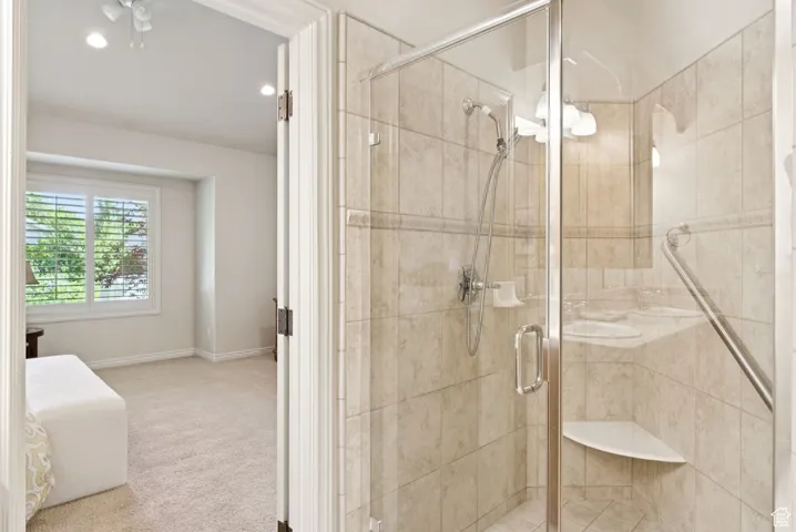 Bathroom featuring a shower stall and a ceiling fan