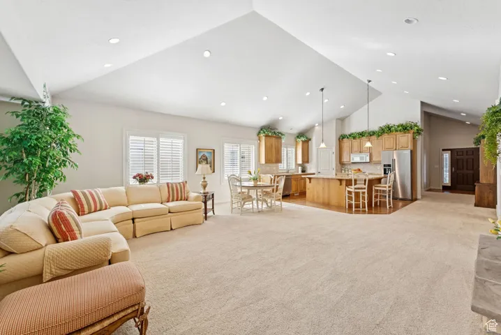 Living room with high vaulted ceiling, light colored carpet, and recessed lighting