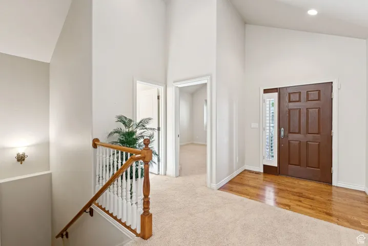 Carpeted foyer featuring high vaulted ceiling and baseboards