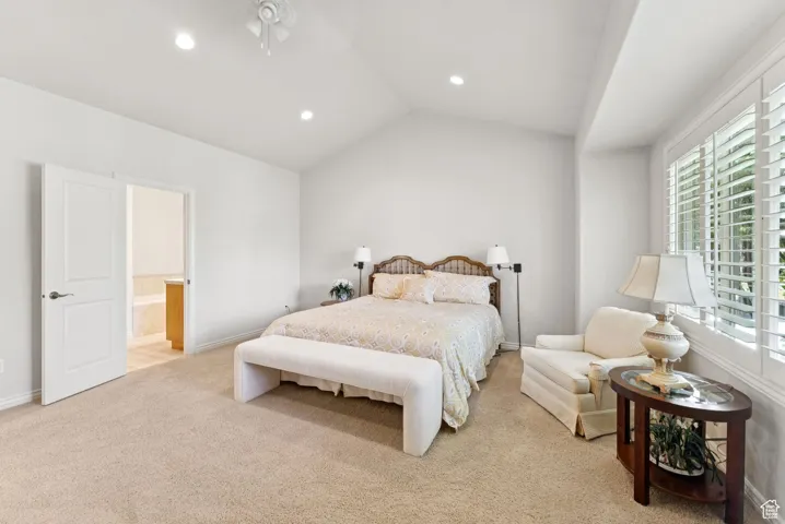 Bedroom featuring multiple windows, light carpet, recessed lighting, lofted ceiling, and ensuite bathroom