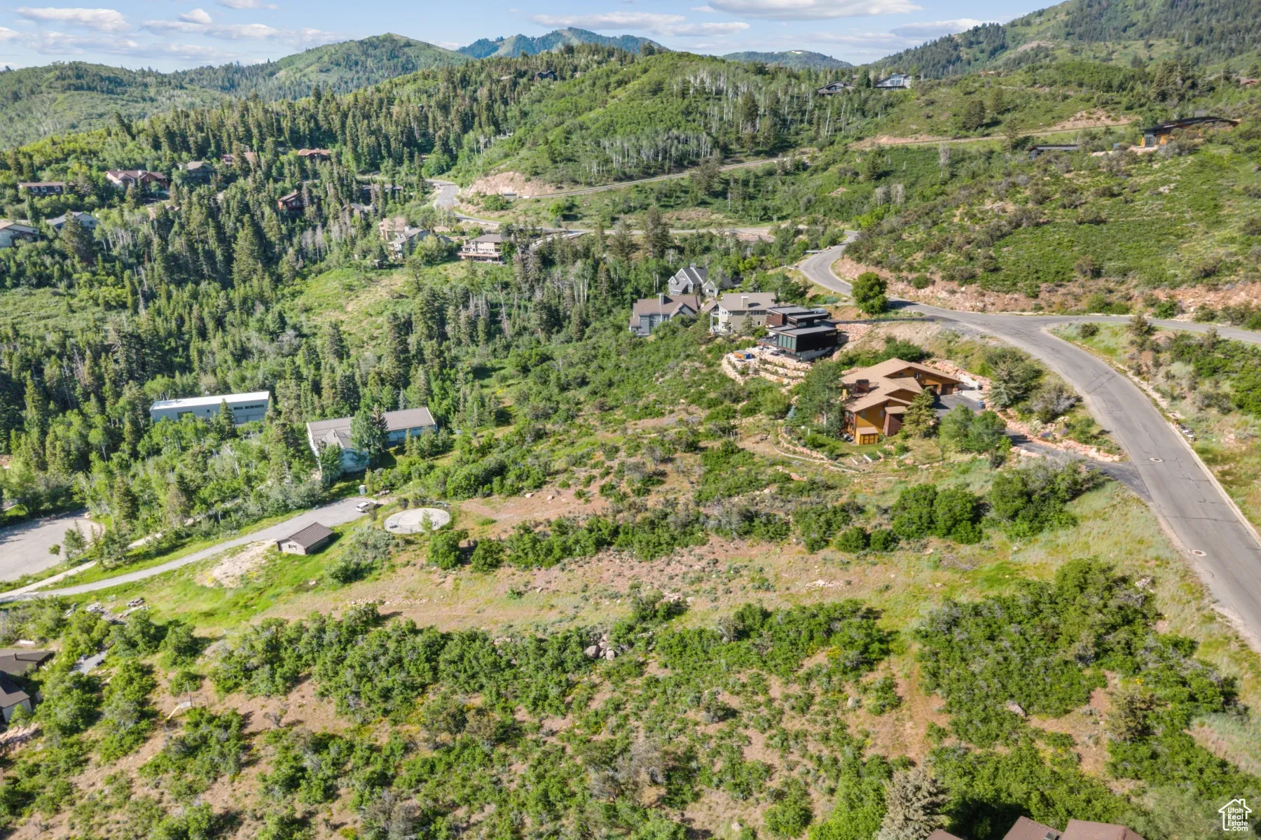 Aerial overview of property's location featuring mountains and a forest