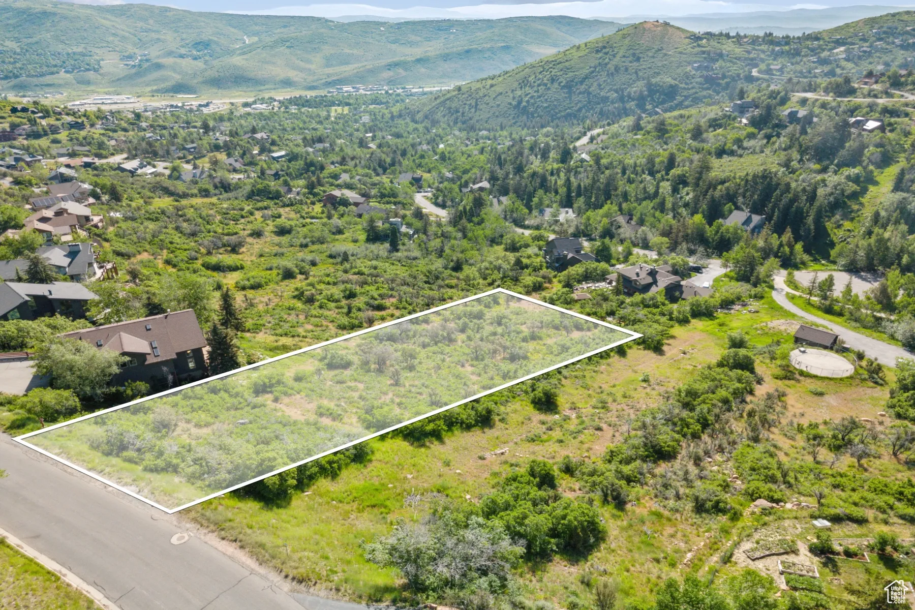 Aerial view of property and surrounding area featuring a mountainous background and property boundaries highlighted