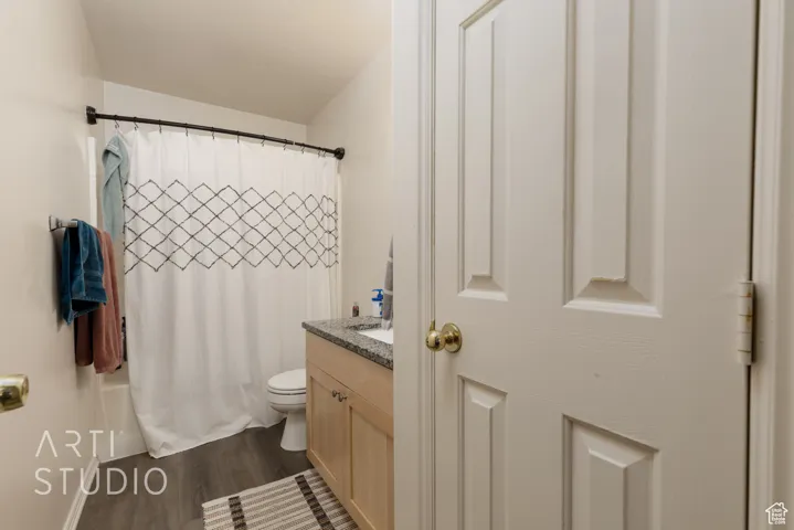 Full bathroom with wood finished floors, vanity, and shower / bathtub combination with curtain