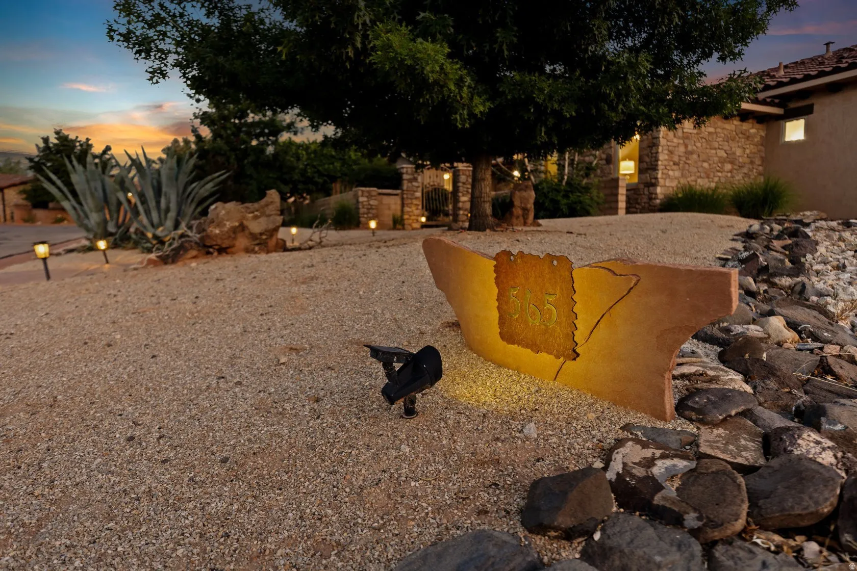 Gravel landscaping featuring a custom address marker and perimeter rock detailing