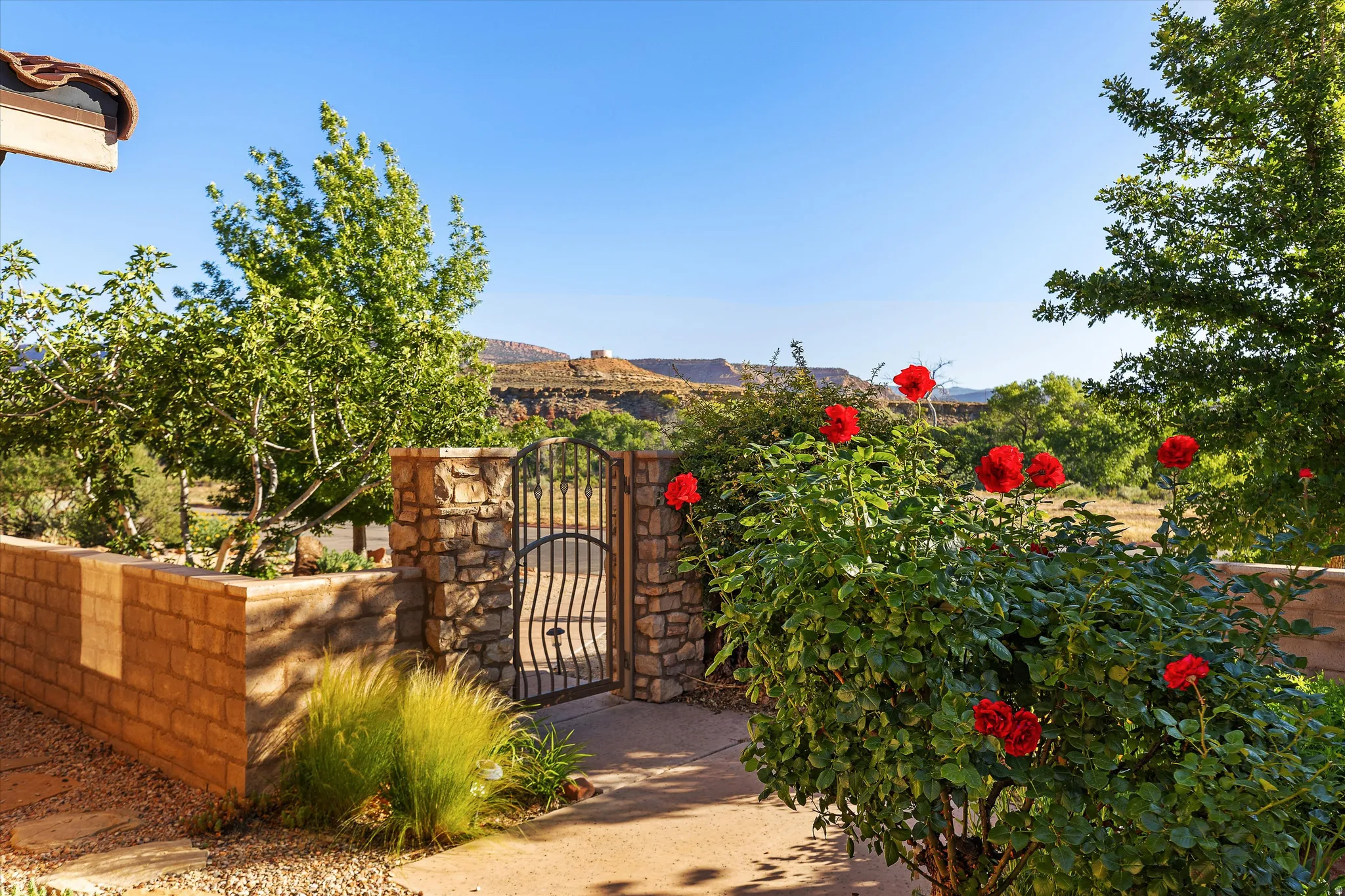 Wrought iron gate set within stone columns, complemented by a block retaining wall