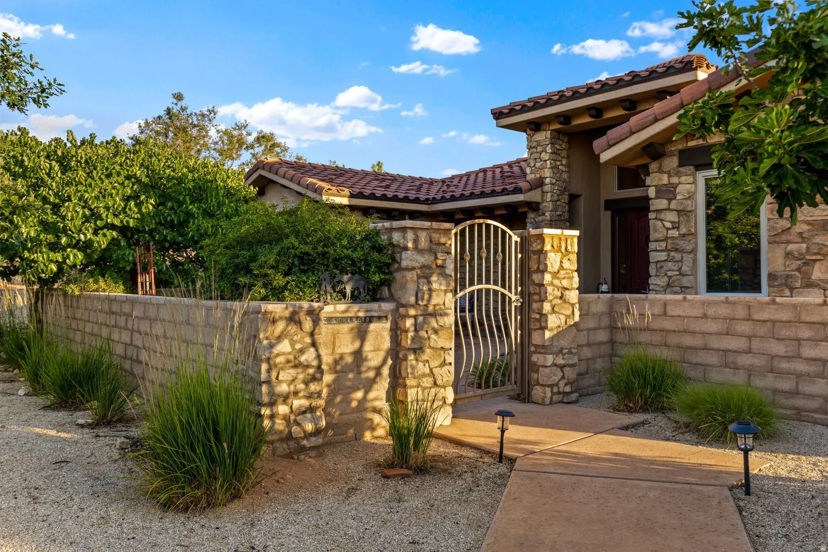Stone facade residence featuring a tiled roof and an ornate wrought iron gate