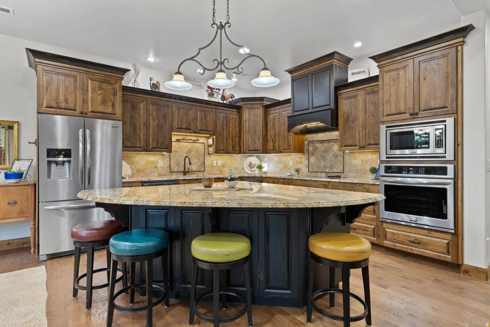 Spacious kitchen featuring an expansive island with a light-toned countertop, dark wood-finish cabinetry, stainless steel appliances, a tiled backsplash, and wood-finish flooring