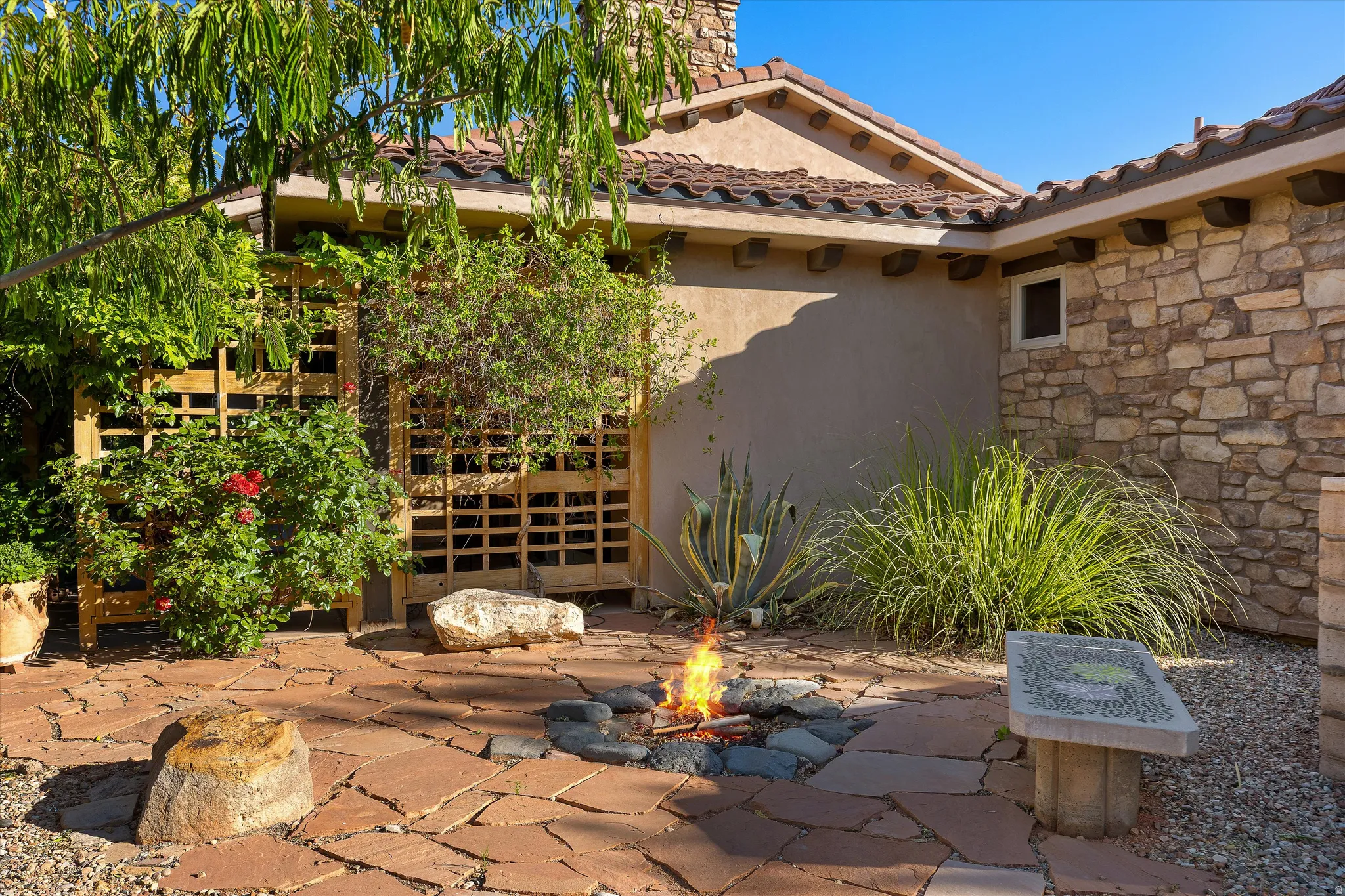 Flagstone patio featuring a built-in fire pit, stone accent wall, and decorative wooden lattice