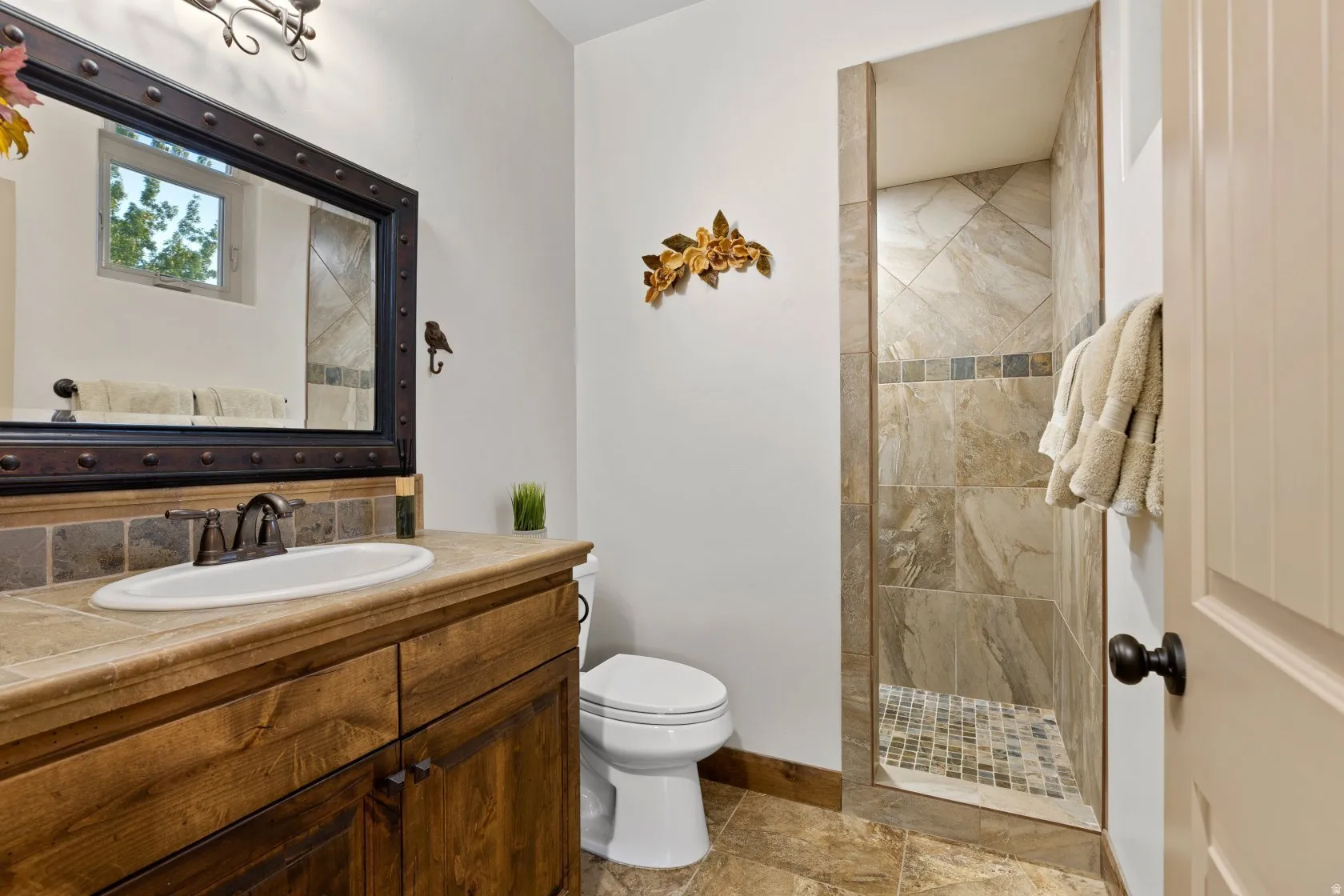 Walk-in shower with natural stone-look tile surround and mosaic tile floor