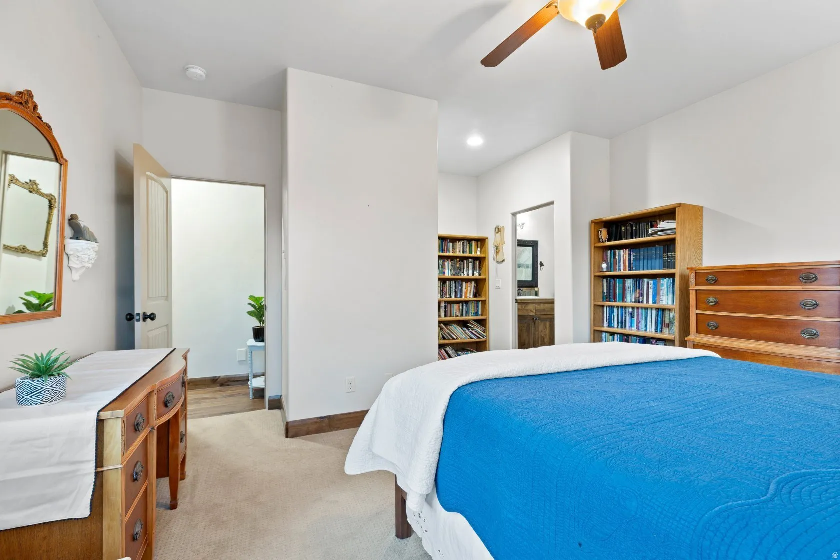 Carpeted room with a ceiling fan light fixture, light wood baseboards, and built-in bookshelves