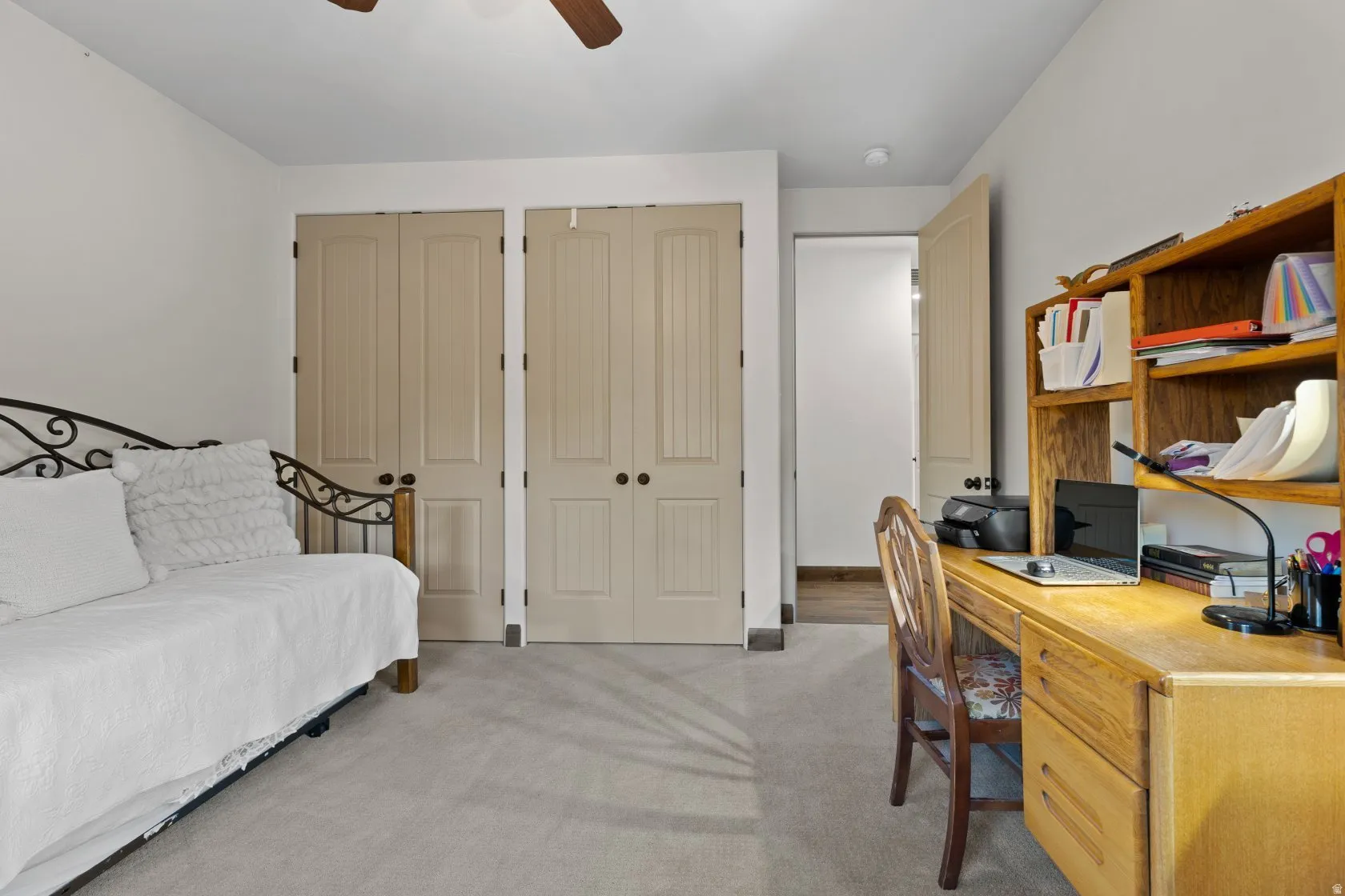 Interior room featuring light-toned carpet flooring, white walls, and a ceiling fan